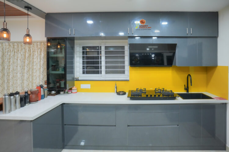 Modern kitchen interior with gray cabinets, yellow backsplash, and stainless steel appliances.