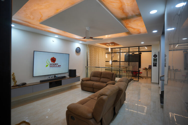 Modern living room with glossy floor tiles, a large tv Unit, a comfortable brown sofa and a False Ceiling